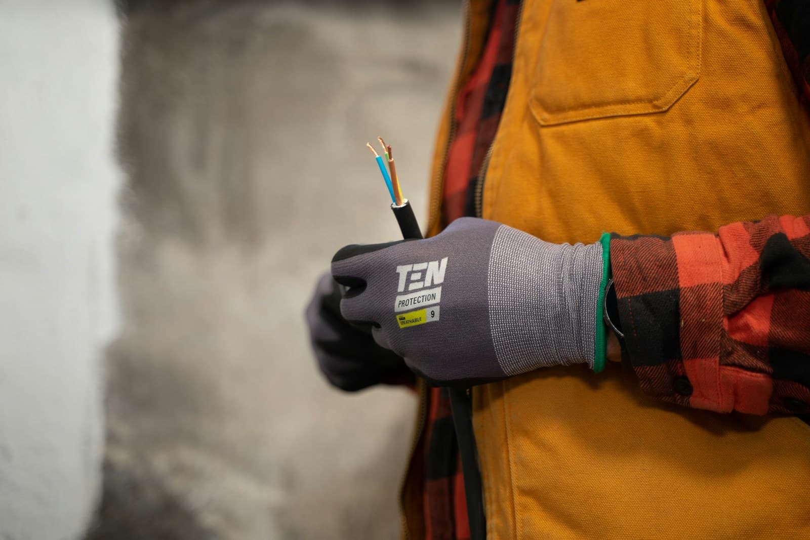 Electrician in work gloves holding a stripped electrical cable