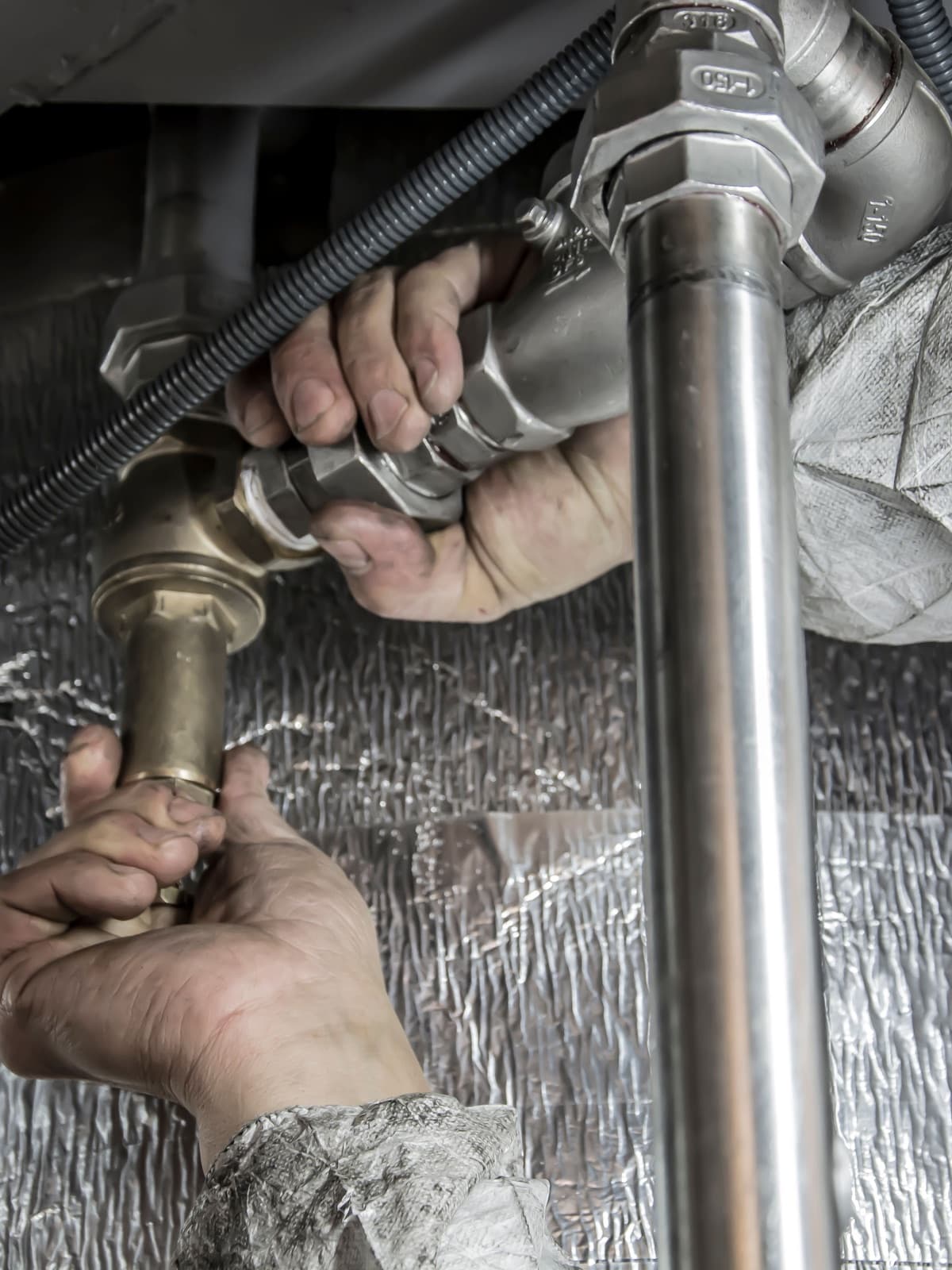 Close-up of hands tightening plumbing pipe fittings.
